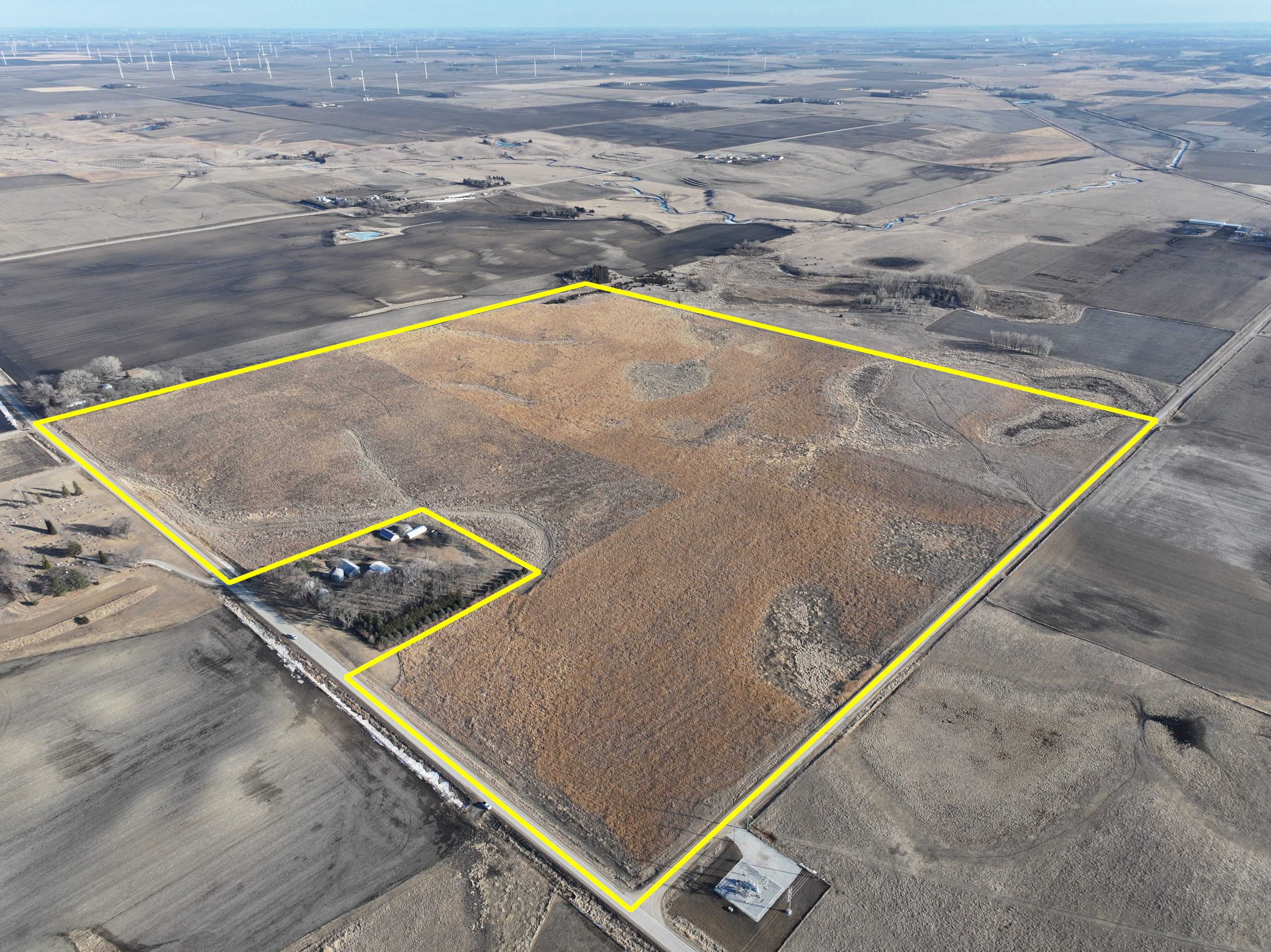 Aerial view of a large, rectangular land parcel with a small farmstead.