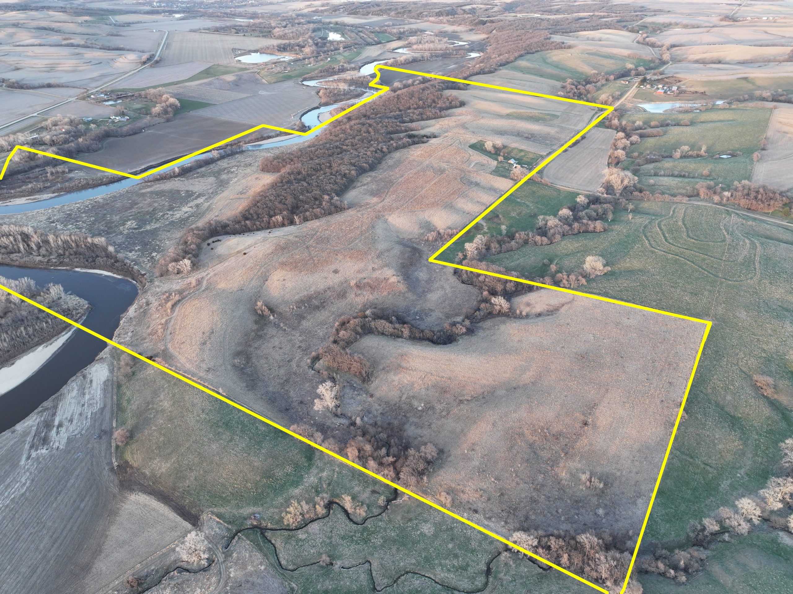 Aerial view of a large, irregular parcel of land bordering a river.