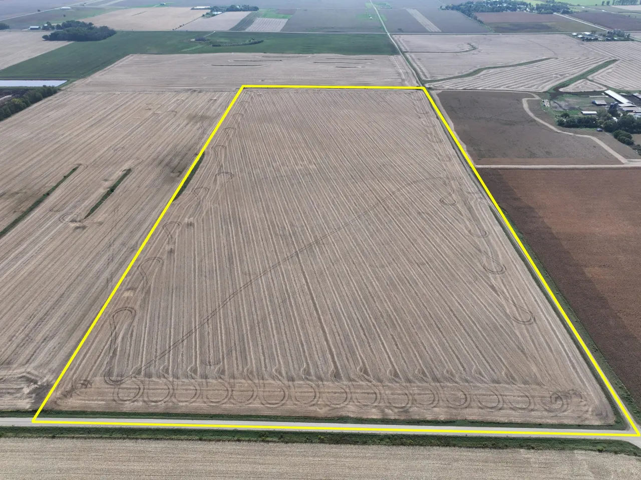 Aerial view of a large, rectangular plowed field outlined in yellow, surrounded by other fields. The landscape appears flat and expansive.