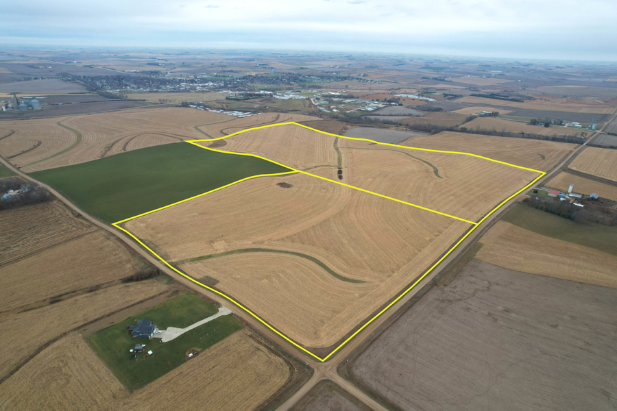 Aerial view of a farmland tract outlined in yellow near Spencer, Iowa, with a farmstead and small town visible in the distance.