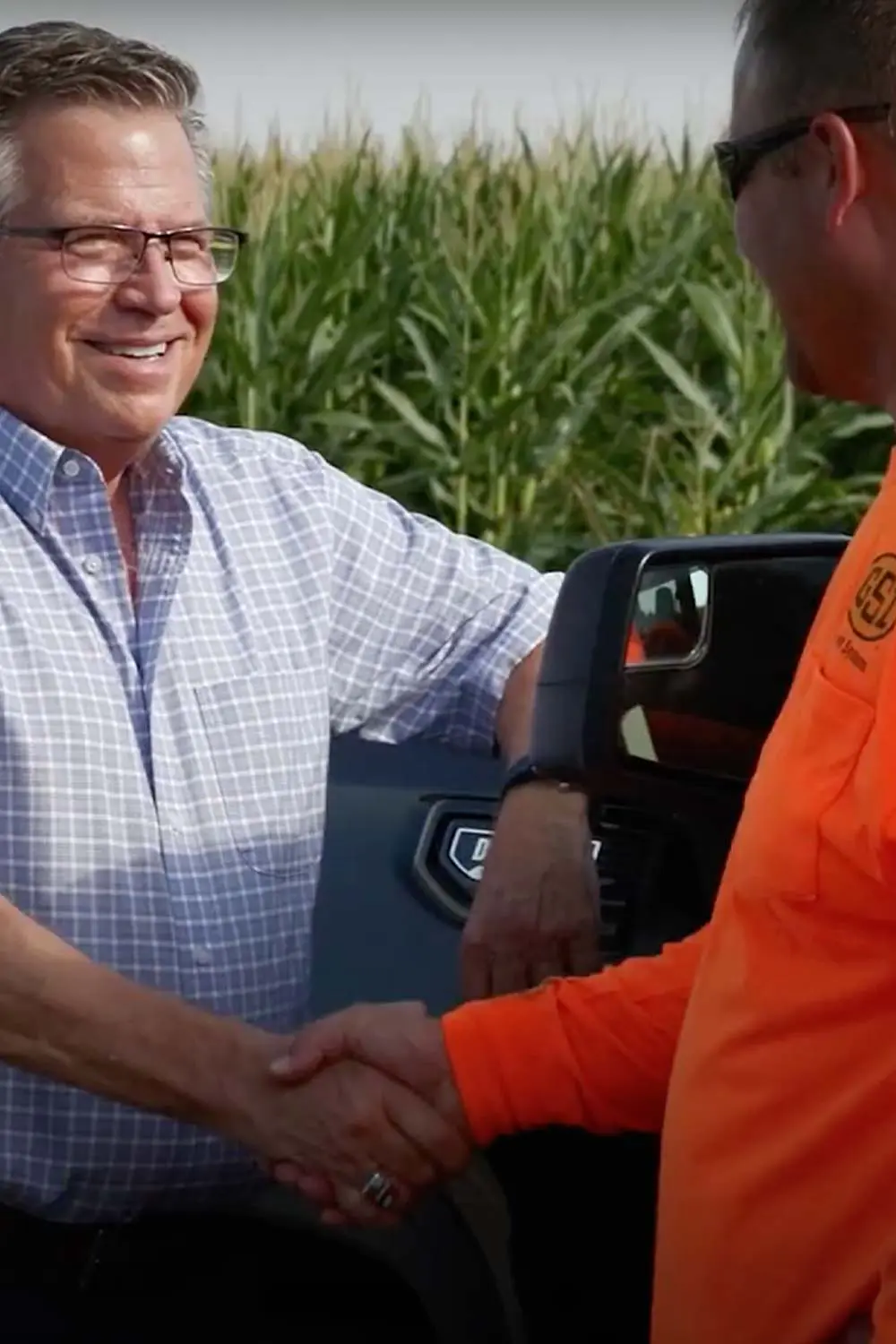 farm-sale An Acre Company team member shaking hands with a landowner in front of a cornfield, closing a farm sale